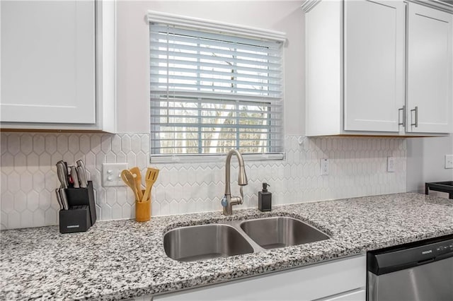 kitchen with light stone counters, sink, stainless steel dishwasher, and white cabinets