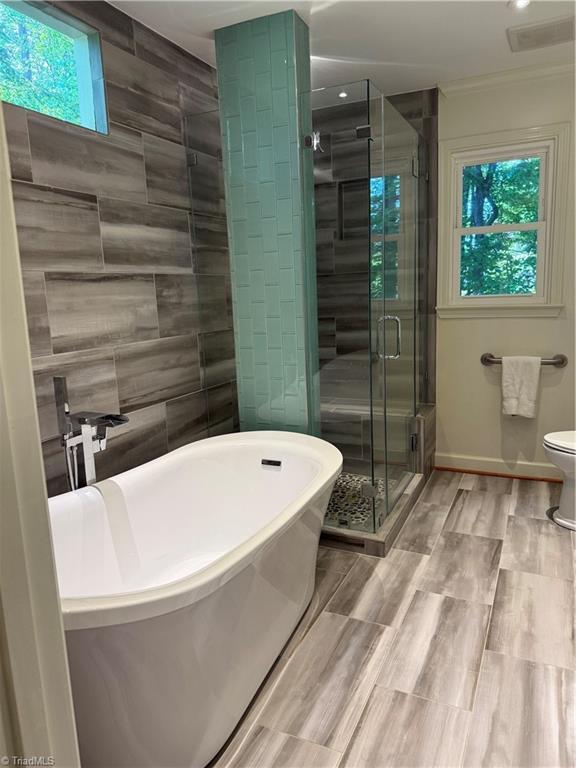 1005 Stuart Dr, Mebane, NC 27302 - bathroom with toilet, a shower stall, a soaking tub, and wood finished floors