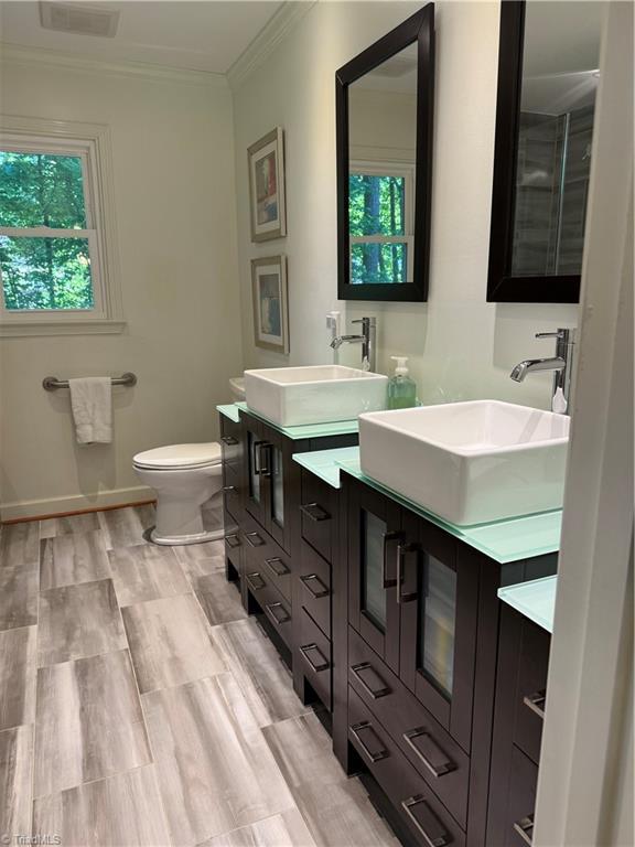 1005 Stuart Dr, Mebane, NC 27302 - bathroom featuring crown molding, toilet, a sink, and double vanity