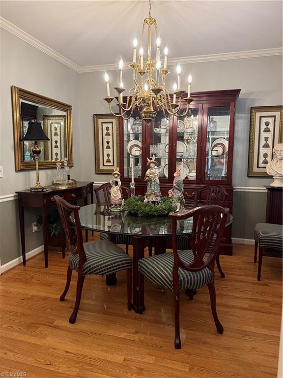 1005 Stuart Dr, Mebane, NC 27302 - dining space with crown molding, baseboards, wood finished floors, and a chandelier
