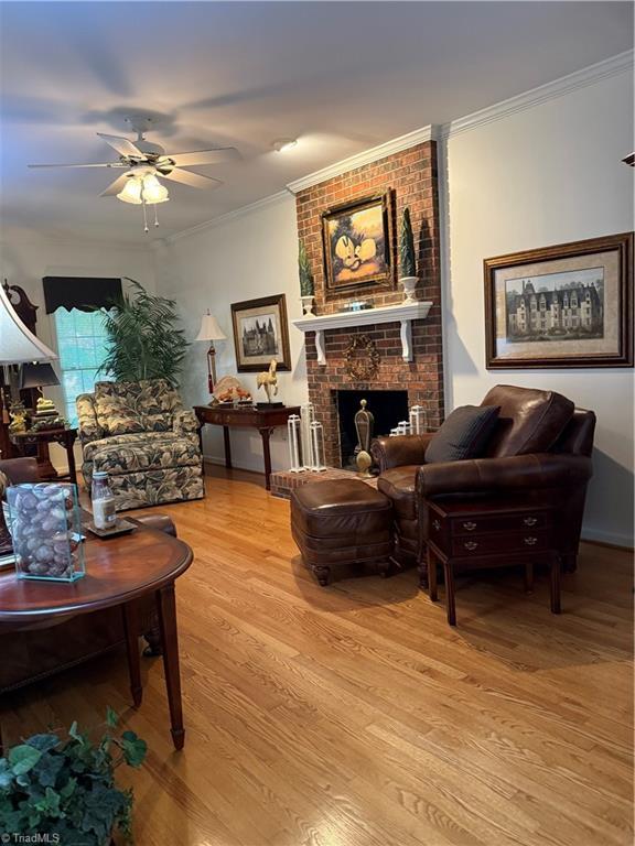 1005 Stuart Dr, Mebane, NC 27302 - living area with a fireplace, a ceiling fan, ornamental molding, and light wood-style floors