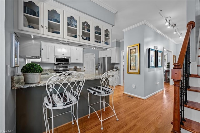 1005 Stuart Dr, Mebane, NC 27302 - kitchen featuring crown molding, a peninsula, glass insert cabinets, light wood-type flooring, and appliances with stainless steel finishes
