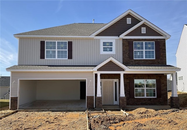 craftsman house featuring an attached garage, driveway, and roof with shingles