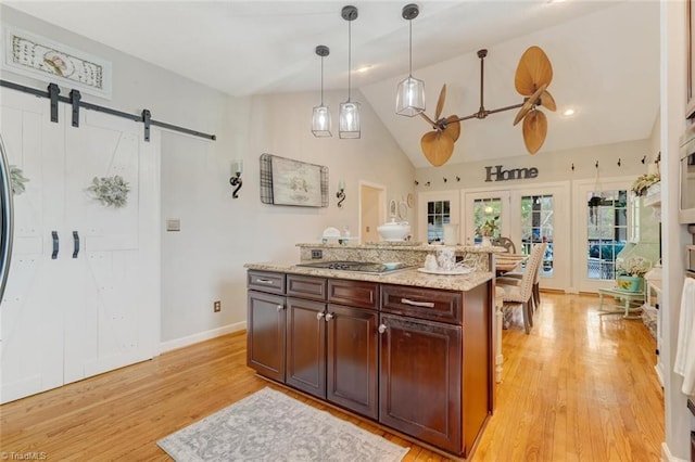 kitchen featuring light wood-type flooring, hanging light fixtures, a barn door, and gas stovetop