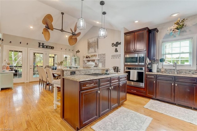 kitchen featuring stainless steel appliances, plenty of natural light, decorative light fixtures, and lofted ceiling