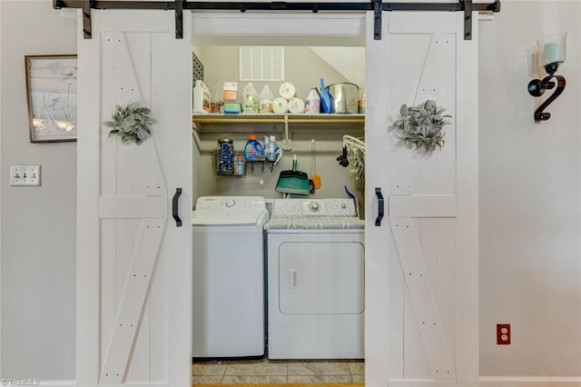 clothes washing area with a barn door and washing machine and dryer