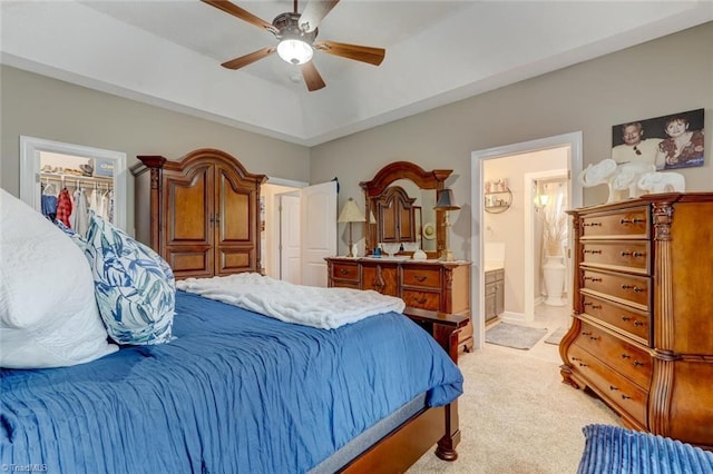 bedroom with ensuite bathroom, light colored carpet, ceiling fan, and a closet