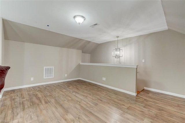 additional living space featuring light hardwood / wood-style floors, a notable chandelier, and vaulted ceiling