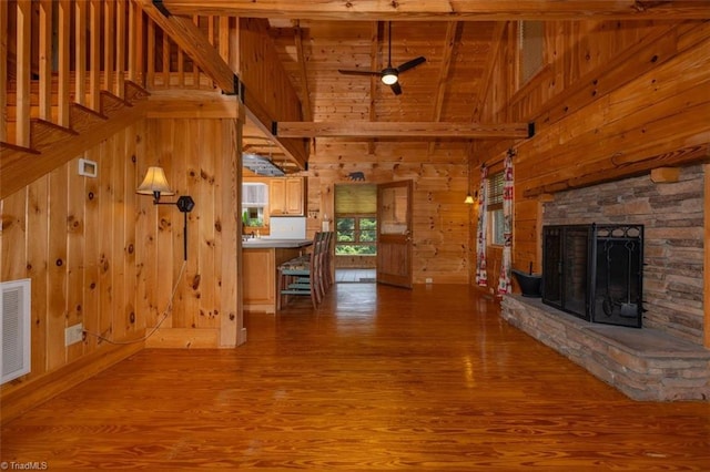 158 Cottontail Ln, North Wilkesboro, NC 28659 - unfurnished living room featuring wooden walls, wood finished floors, high vaulted ceiling, a stone fireplace, and ceiling fan