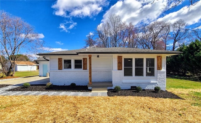 view of front facade featuring a front yard, crawl space, brick siding, and a chimney