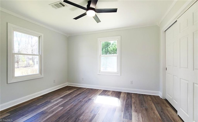 unfurnished bedroom with dark wood-style flooring, a closet, visible vents, and baseboards