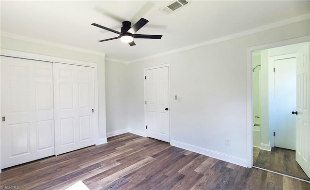 unfurnished bedroom featuring baseboards, visible vents, dark wood-type flooring, crown molding, and a closet