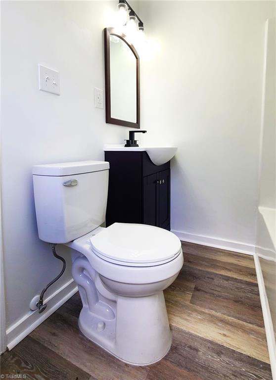 bathroom with toilet, baseboards, wood finished floors, and vanity