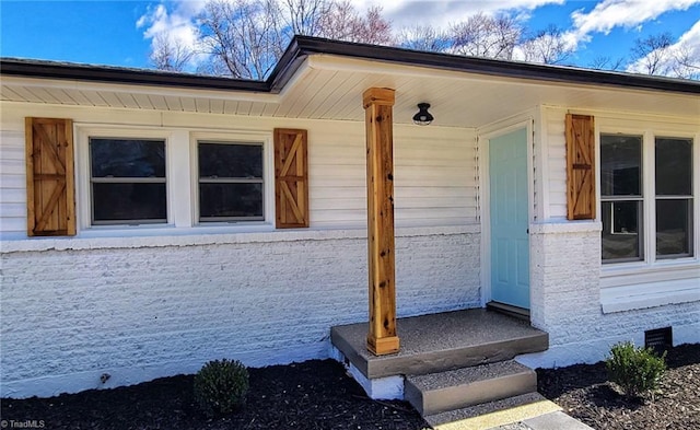 doorway to property with crawl space and brick siding