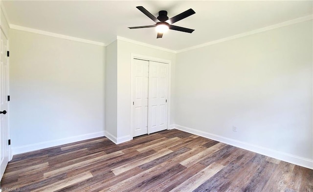 unfurnished bedroom with a closet, ornamental molding, ceiling fan, wood finished floors, and baseboards