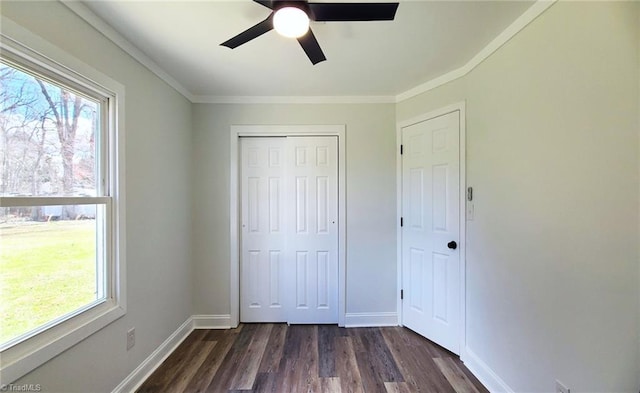 unfurnished bedroom featuring multiple windows, baseboards, and dark wood-type flooring