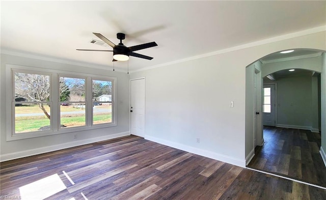 unfurnished room featuring baseboards, arched walkways, dark wood finished floors, and crown molding