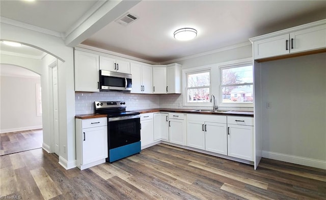 kitchen featuring tasteful backsplash, arched walkways, visible vents, stainless steel appliances, and a sink