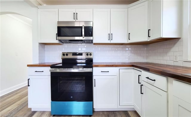 kitchen with butcher block counters, light wood-type flooring, appliances with stainless steel finishes, and white cabinetry