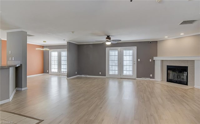 unfurnished living room featuring a fireplace, visible vents, ornamental molding, light wood-style floors, and baseboards