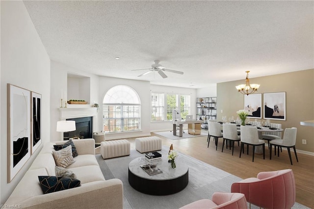 4290 Cedarcroft Ct Unit 2A, Greensboro, NC 27409 - living room featuring wood finished floors, a textured ceiling, a chandelier, a glass covered fireplace, and ceiling fan