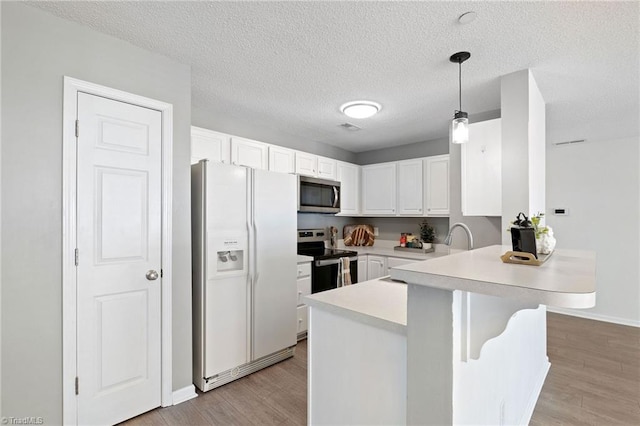 4290 Cedarcroft Ct Unit 2A, Greensboro, NC 27409 - kitchen featuring appliances with stainless steel finishes, a peninsula, white cabinetry, light countertops, and light wood finished floors