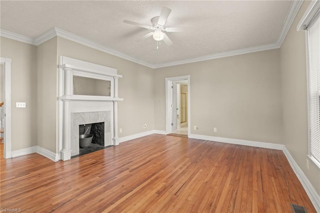 unfurnished living room with ceiling fan, a high end fireplace, light hardwood / wood-style floors, a textured ceiling, and ornamental molding