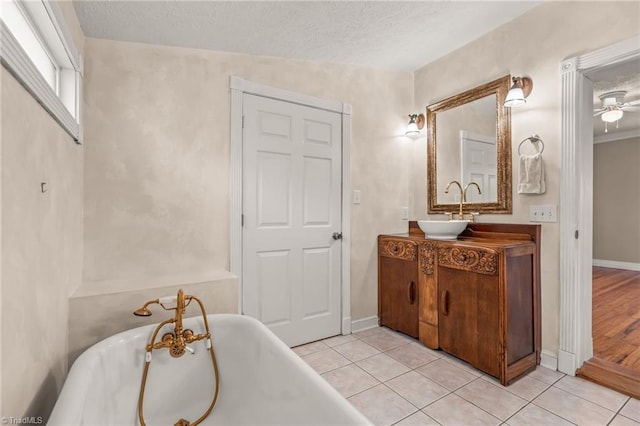 bathroom with oversized vanity, tile flooring, a bath, ceiling fan, and a textured ceiling