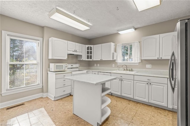 kitchen with light tile floors, a center island, white appliances, white cabinets, and sink