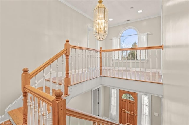 stairs with ornamental molding and a notable chandelier