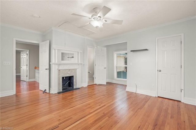 unfurnished living room with ceiling fan, a premium fireplace, light wood-type flooring, and crown molding