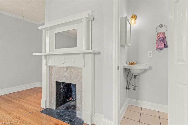 interior space with light hardwood / wood-style flooring, a tile fireplace, and ornamental molding