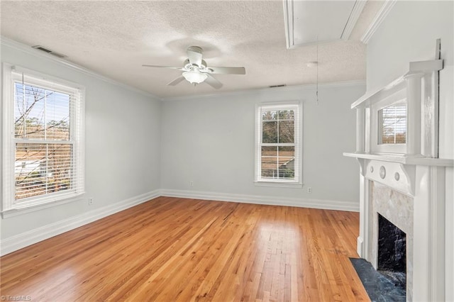 unfurnished living room featuring plenty of natural light, ceiling fan, light hardwood / wood-style flooring, and a premium fireplace