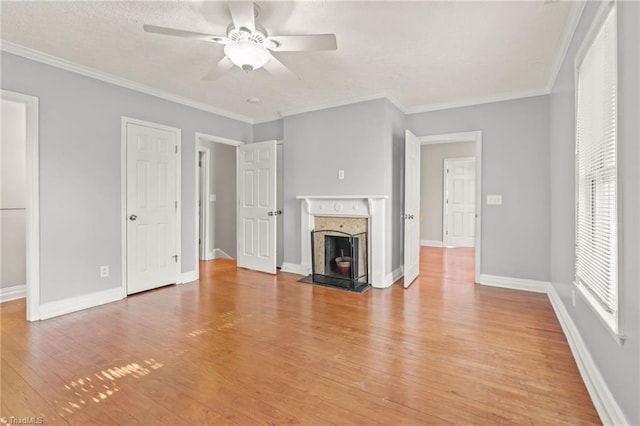 unfurnished living room with a healthy amount of sunlight, ceiling fan, light hardwood / wood-style flooring, and a premium fireplace