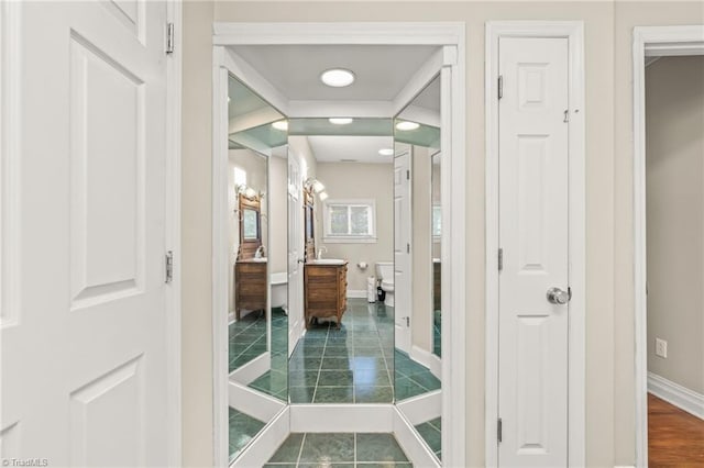 hallway with dark tile floors and sink