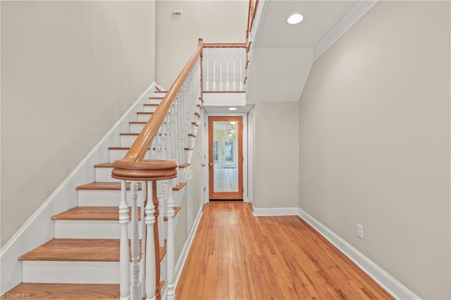 staircase with crown molding and light hardwood / wood-style flooring