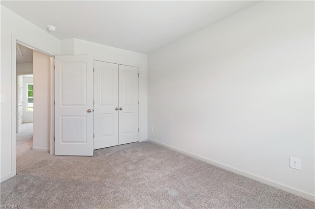 unfurnished bedroom with a closet, carpet, and baseboards