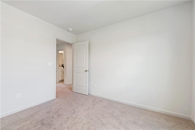 empty room featuring light carpet and baseboards