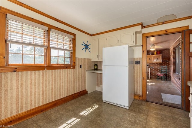 kitchen featuring a wood stove, white cabinetry, ceiling fan, white refrigerator, and ornamental molding