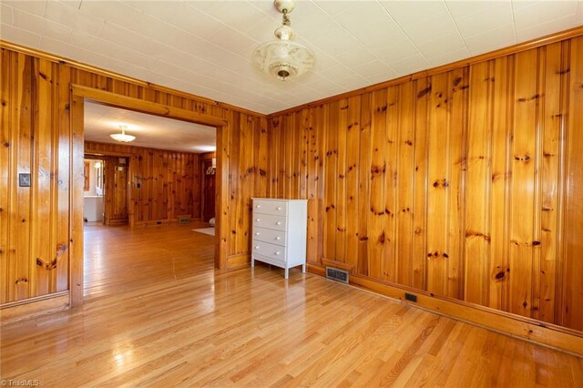 empty room with wooden walls and light hardwood / wood-style flooring