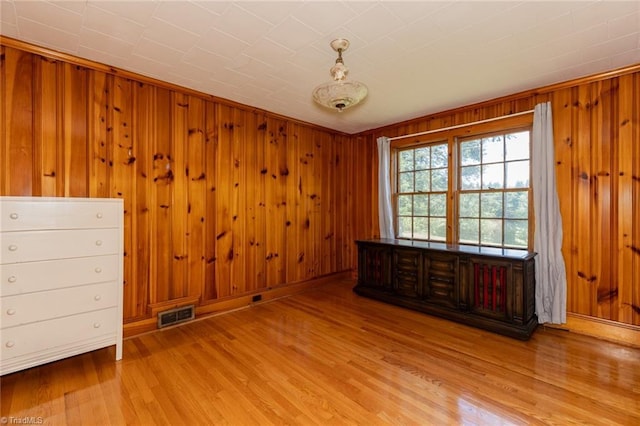 unfurnished room featuring light wood-type flooring and wooden walls