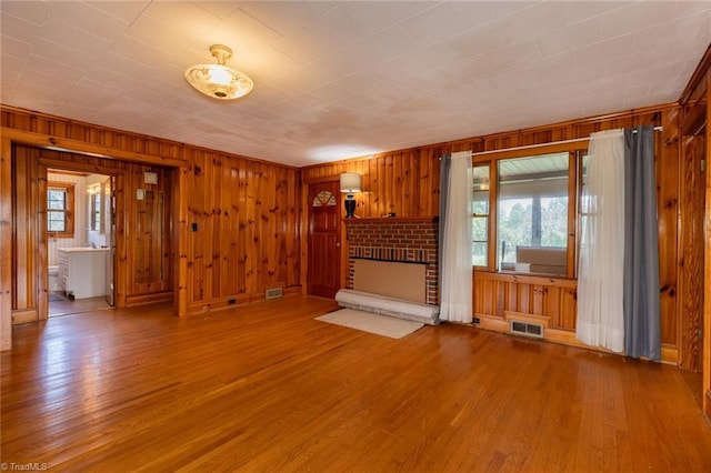 unfurnished living room with wood walls, a fireplace, and light wood-type flooring