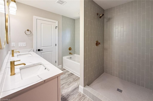 bathroom with visible vents, a tile shower, and a sink