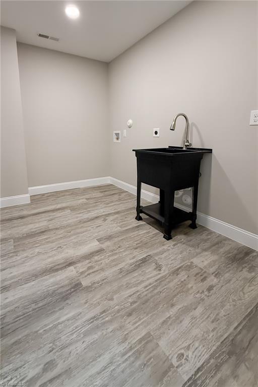 interior space with wood finished floors, visible vents, hookup for an electric dryer, laundry area, and washer hookup