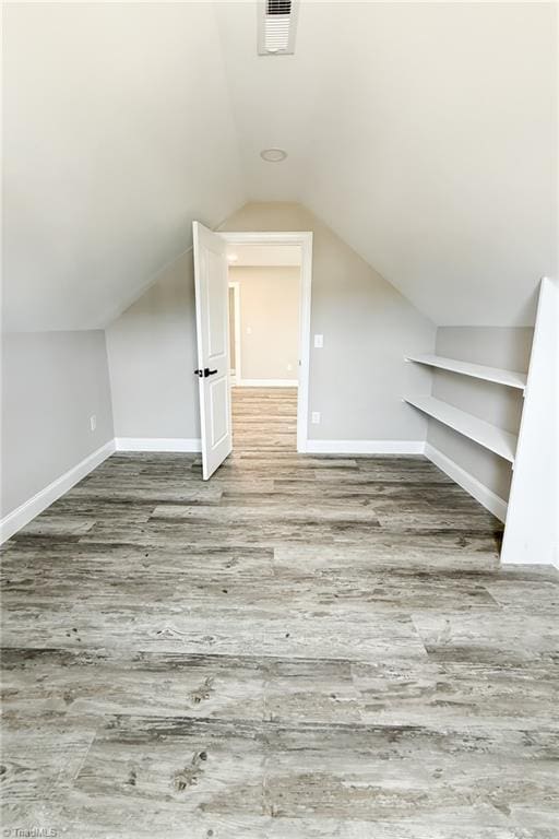 bonus room with visible vents, baseboards, lofted ceiling, and wood finished floors