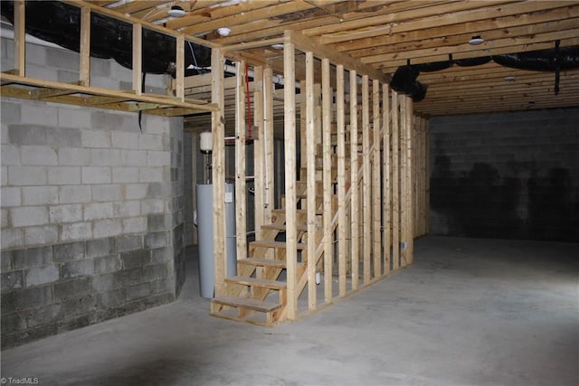 unfinished below grade area featuring concrete block wall and water heater