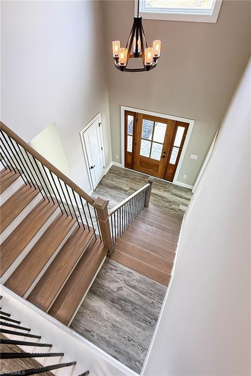 entryway with baseboards, stairs, a high ceiling, wood finished floors, and a notable chandelier