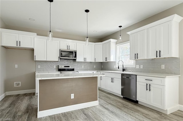 kitchen with a sink, stainless steel appliances, light countertops, white cabinets, and light wood-type flooring