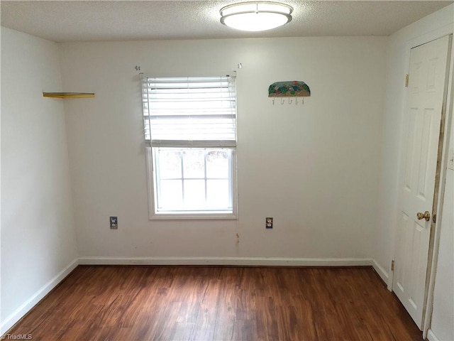 spare room with dark wood-type flooring and a textured ceiling