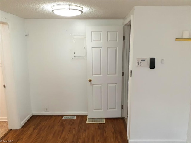 spare room with dark hardwood / wood-style flooring, a textured ceiling, and electric panel